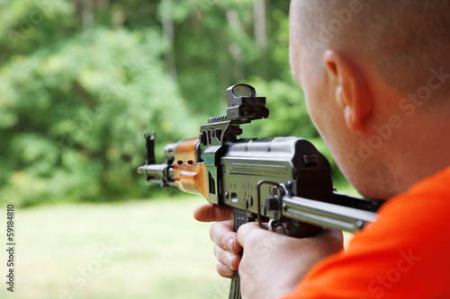 Man aiming at a target and shooting an automatic rifle for strik