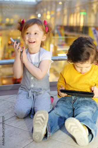 Little pretty girl with mobile phone and boy with tablet pc