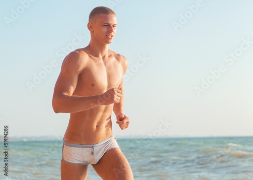 Running man jogging on beach. Male runner training outside