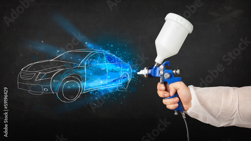 Worker with airbrush gun painting hand drawn car lines