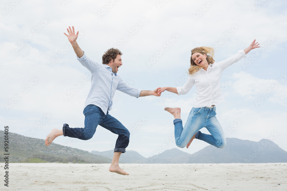 Cheerful couple holding hands and jumping at beach Cheerful couple holding hands and jumping at beach