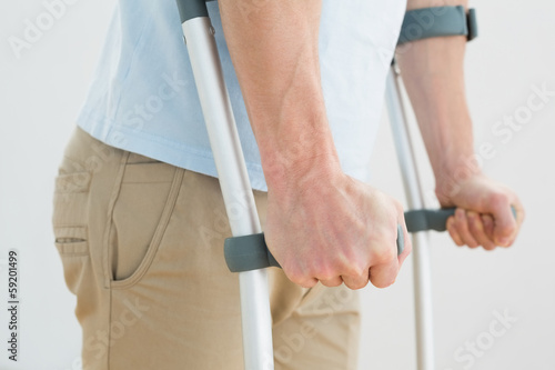 Close-up mid section of a man with crutches