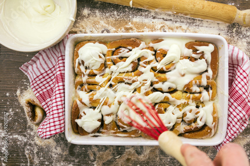 Glazing cinnamon rolls with icing from whisk