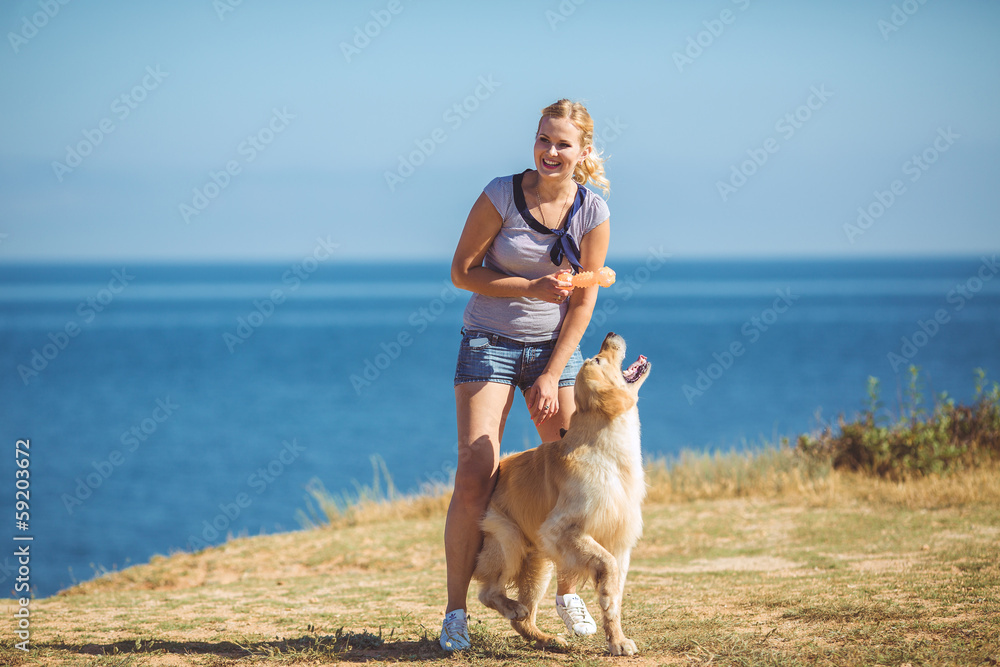Beautiful woman with her dog playing on the sea shore. Outdoor p Beautiful woman with her dog playing on the sea shore. Outdoor p