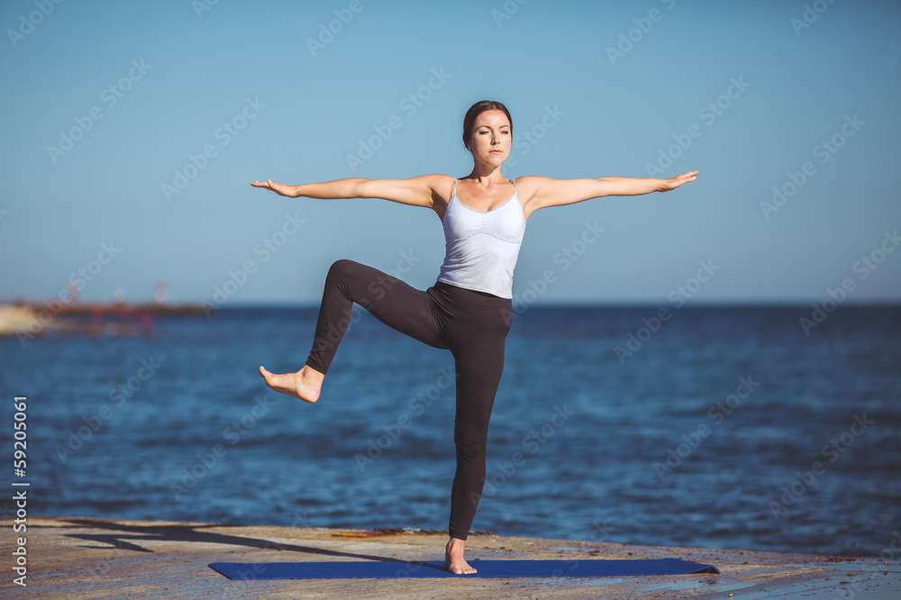 Young beautiful woman on the beach making yoga Young beautiful woman on the beach making yoga