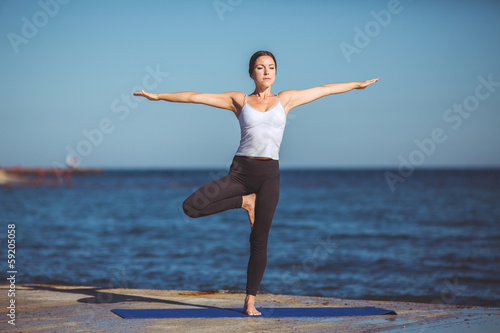 Young beautiful woman on the beach making yoga © GTeam