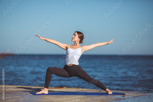 Young beautiful woman on the beach making yoga