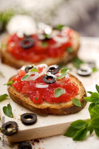 Bruschetta with tomatoes, black olives, onion and herbs