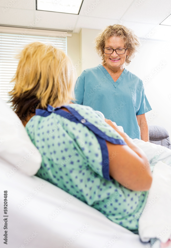 Obraz premium Happy Nurse Looking At Newborn Babygirl With Mother In Hospital