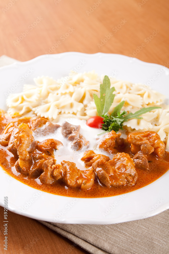 Naklejka premium Pork knuckle of ham with peeled almonds and pasta