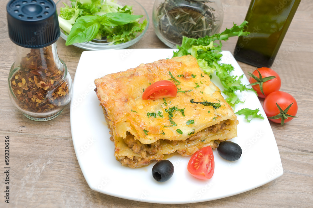 Lasagna with meat, cherry tomatoes, olives and spices on a woode Lasagna with meat, cherry tomatoes, olives and spices on a woode