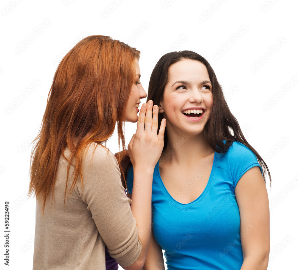 two smiling girls whispering gossip two smiling girls whispering gossip