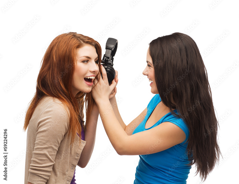 two laughing teenagers sharing headphones two laughing teenagers sharing headphones