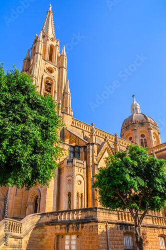 The Ghajnsielem Parish Church behind the trees in Gozo, Malta