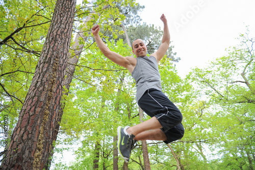 Schilderij op canvas Athletic man jumping in forest
