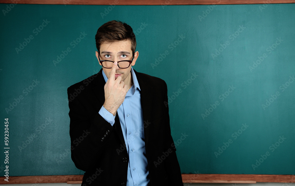 Young teacher near chalkboard in school classroom Young teacher near chalkboard in school classroom