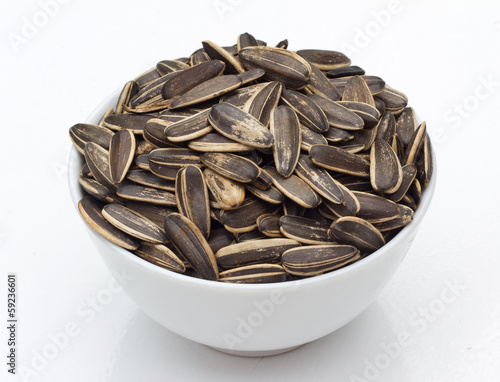 sunflower seeds in bowl on white background