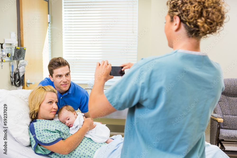 Obraz premium Nurse Photographing Couple With Newborn Baby Through Cellphone