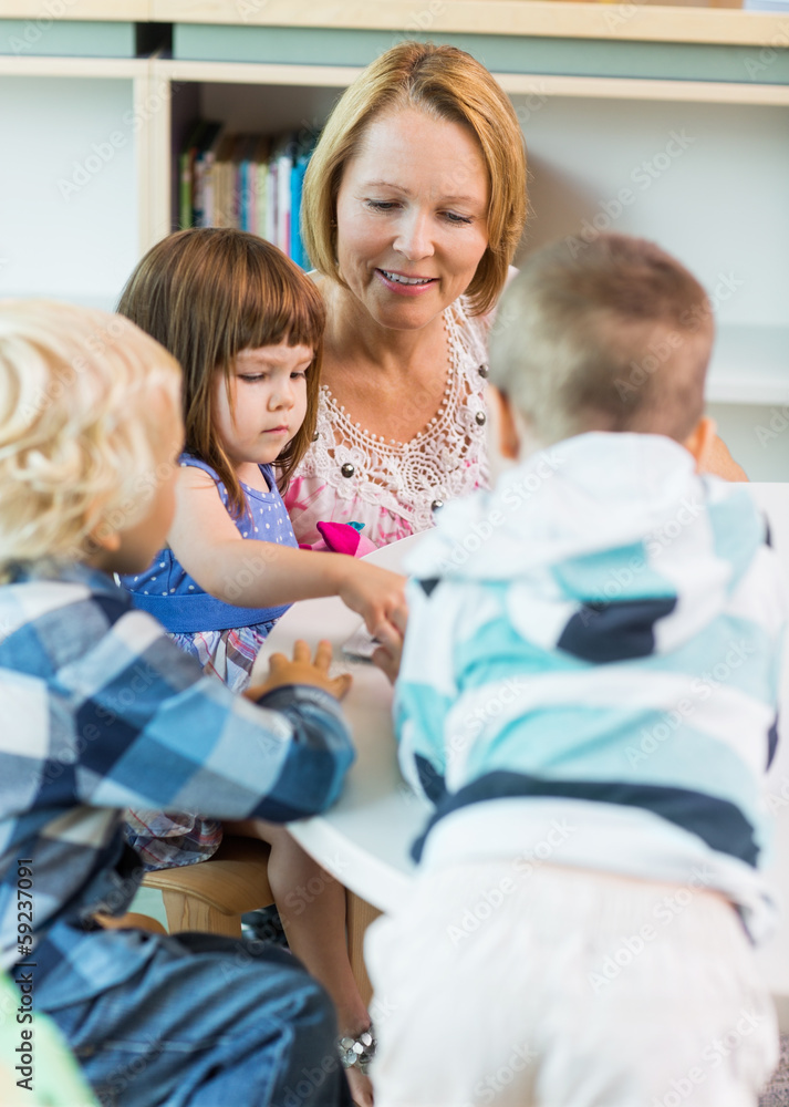 Teacher And Students At Table In Library