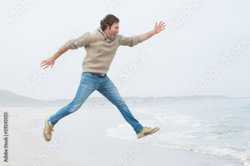 Side view of a casual man jumping at beach