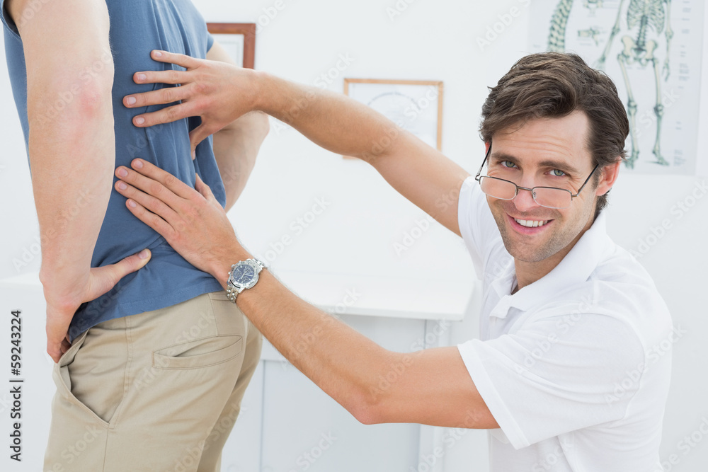 Portrait of a male physiotherapist examining mans back Portrait of a male physiotherapist examining mans back