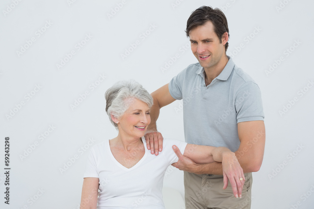 Physiotherapist massaging a smiling senior woman's arm Physiotherapist massaging a smiling senior woman's arm
