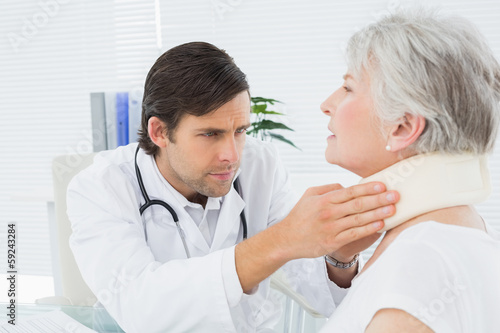 Male doctor examining a senior patient s neck