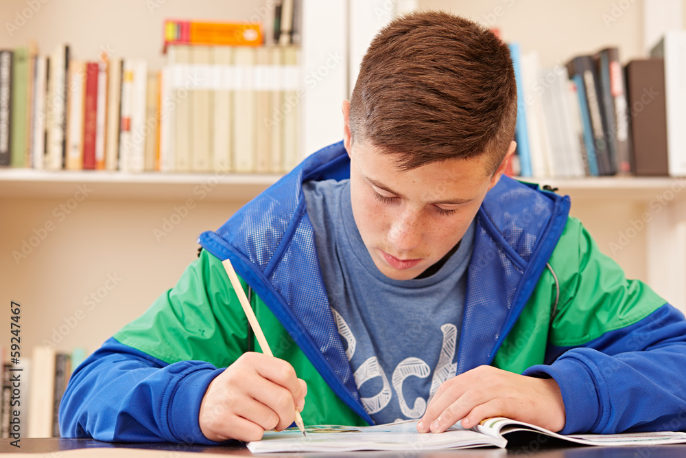 Naklejka premium Male teenager concentrated doing homework