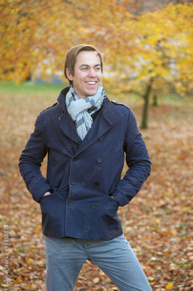 Happy young man smiling outdoors in fall season Happy young man smiling outdoors in fall season