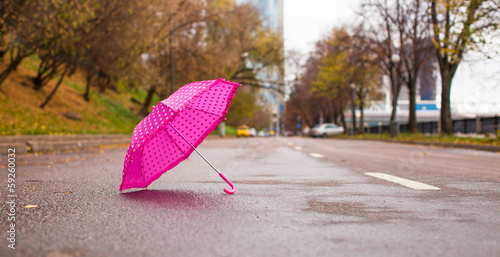 Pink children s umbrella on the wet asphalt outdoors