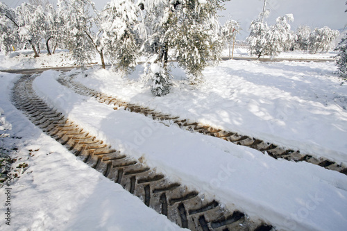 tractor imprints   on a country road in snow , winter