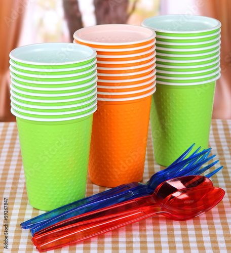 Plastic cups, spoons various colors on bright background