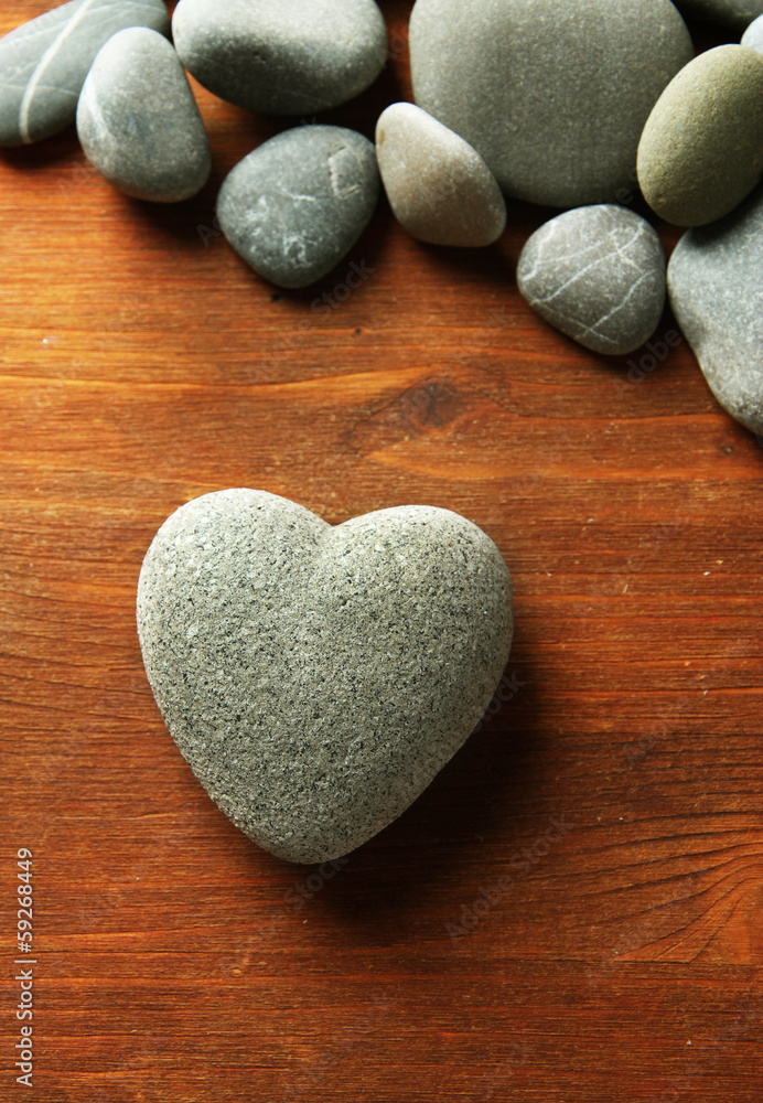 Grey stone in shape of heart, on wooden background Grey stone in shape of heart, on wooden background