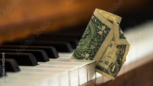 Dirty old one dollar bill stuck in a piano