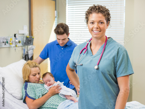 Nurse Standing With Couple And Newborn Baby In Background