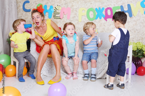 Konstfotografi Four little kids with juice and entertainer sit on sofa