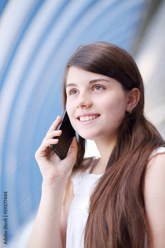 Happy girl in white blouse looks up and talks by mobile phone Happy girl in white blouse looks up and talks by mobile phone