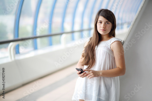 Pretty girl in white blouse with mobile phone looks at camera Free Download Pretty girl in white blouse with mobile phone looks at camera - GFXLoad