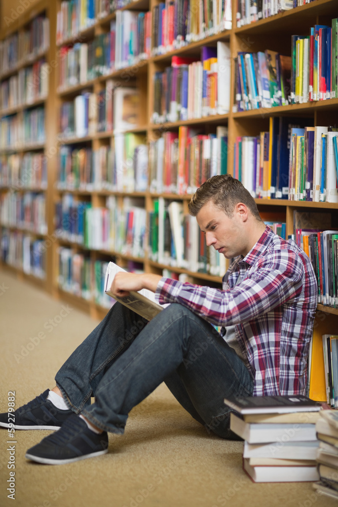 Serious student sitting on library floor reading Serious student sitting on library floor reading