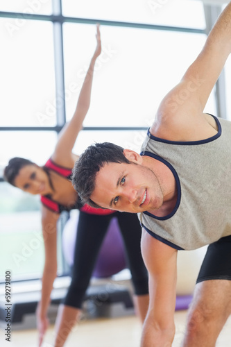 Two sporty people stretching hands at yoga class