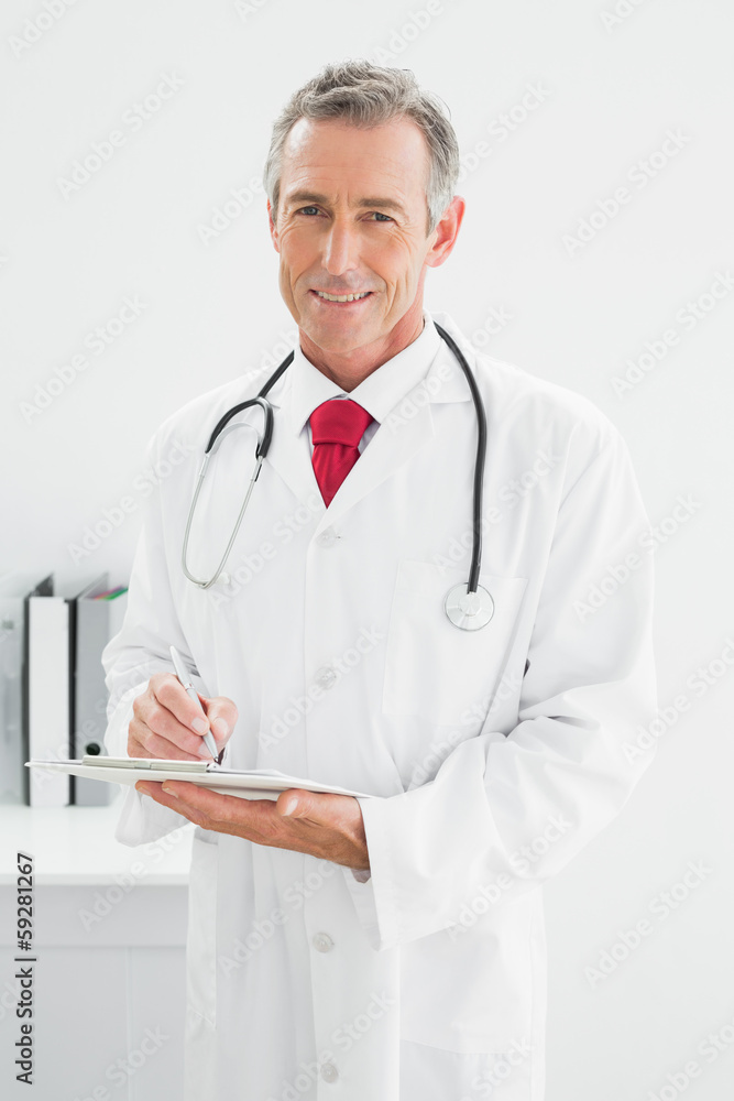 Smiling male doctor writing a report at office Smiling male doctor writing a report at office