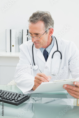 Male doctor writing a report at office