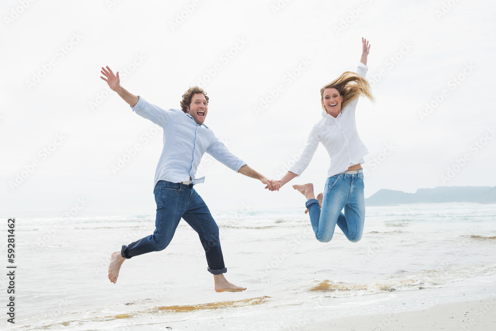 Cheerful couple holding hands and jumping at beach Cheerful couple holding hands and jumping at beach