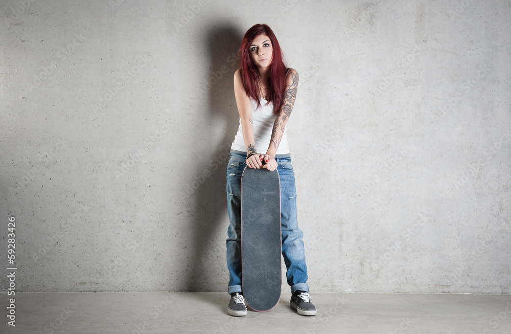 Woman with skateboard portrait against concrete wall. Woman with skateboard portrait against concrete wall.