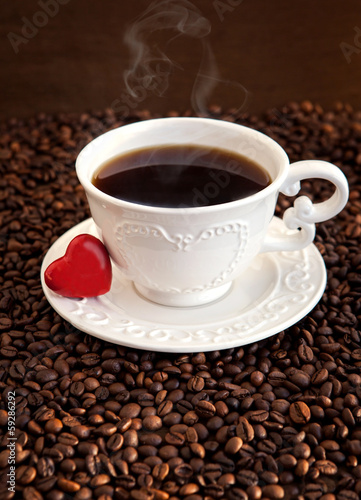 White cup of coffee with red heart on coffee beans