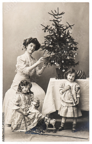 mother and children with christmas tree wearing vintage clothing
