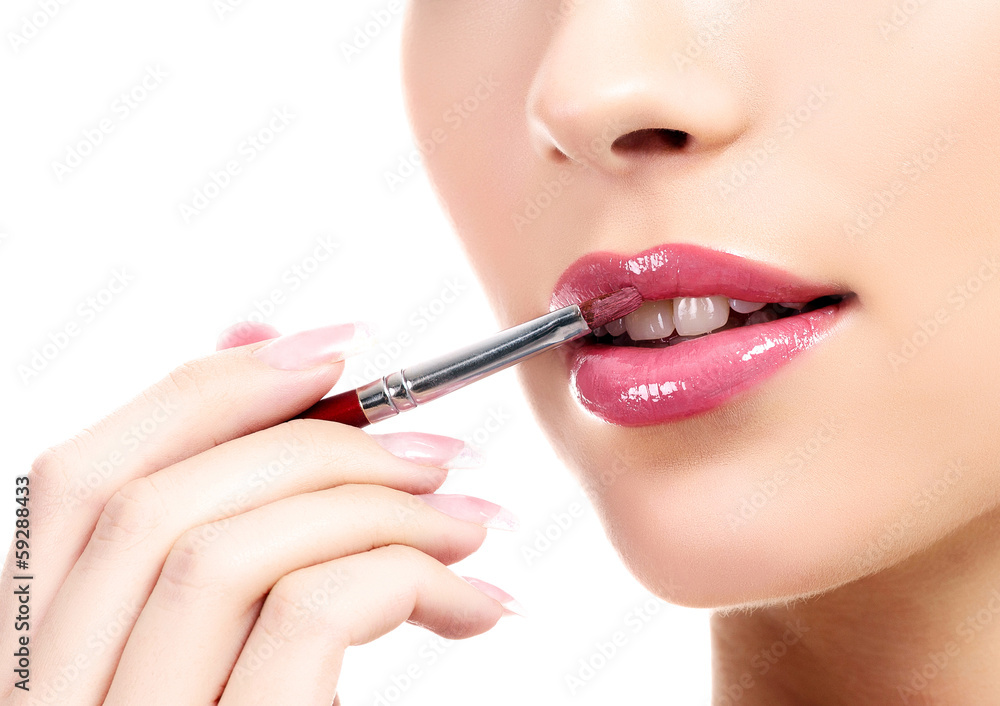 beautiful young woman applying lips makeup with cosmetic brush