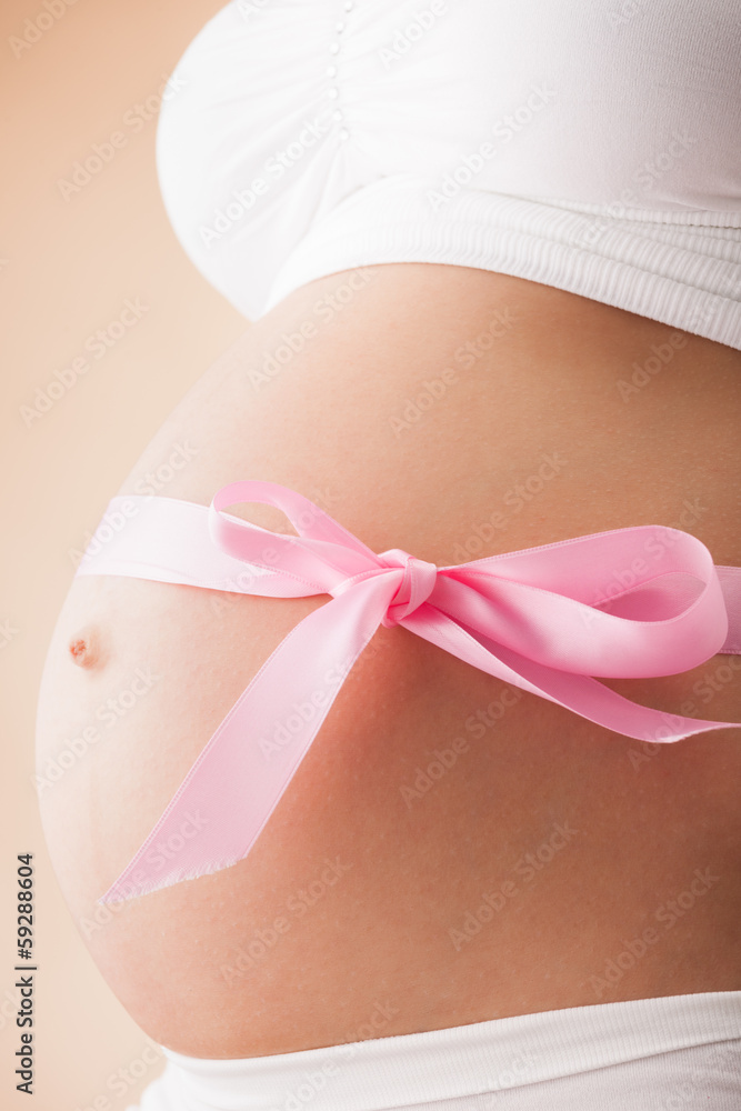 Pregnant belly with pink ribbon. Third trimester. Pregnant belly with pink ribbon. Third trimester.