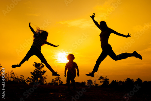 Happy  family jumping on the  road in the  sunset time.
