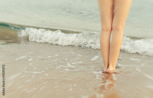 Pair of female legs on a seashore